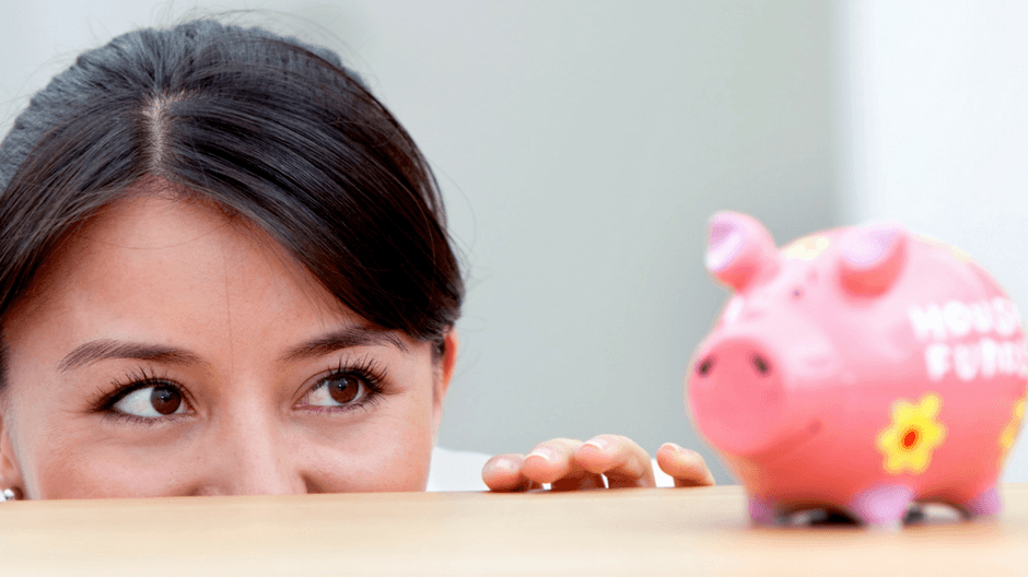 Woman peering over a table at piggy bank