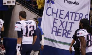 Tom Brady walking past cheater sign