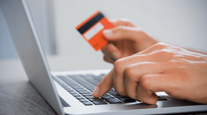 Man using a laptop while holding a debit card