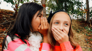 Two girls sharing a surprising secret